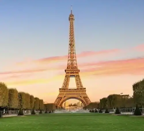 Torre Eiffel en París al atardecer con cielo colorido y jardines verdes.