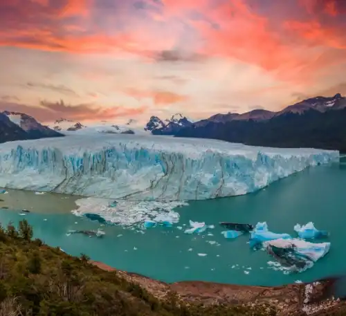 El glaciar Perito Moreno en la Patagonia argentina, con montañas y un atardecer colorido.