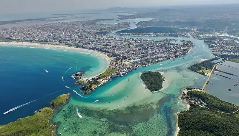 Bahía y río en una vista aérea, con áreas verdes y urbanas en el fondo, en un entorno costero y natu.