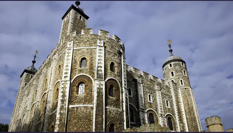 A castle with stone walls and turrets under a cloudy sky.