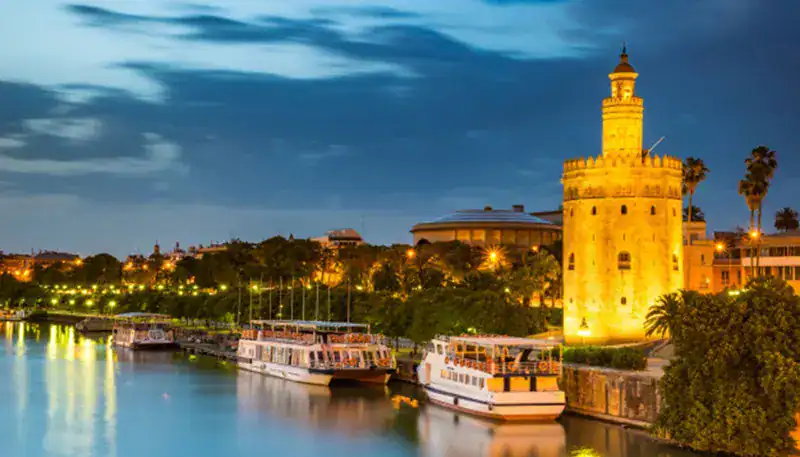 Historic Torre del Oro along the Guadalquivir River in Seville at dusk.